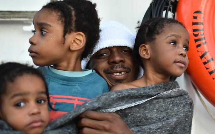 A father holds his three daughters after a rescue operation of migrants off the Libyan coast