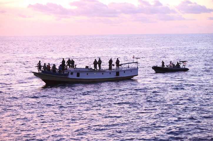 A vessel of interest is boarded at dusk via Rigid Hull Inflatable Boats (RHIB) from HMAS Wollongong